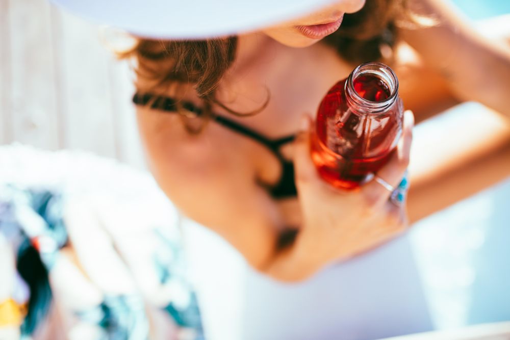 Woman in a swimsuit holding her drink on a sunny day