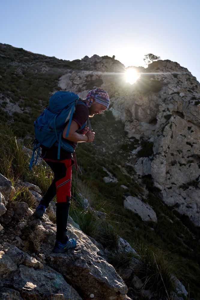 Male hiker with backpack standing on cliff