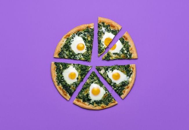 Top view of sliced pizza with spinach and eggs