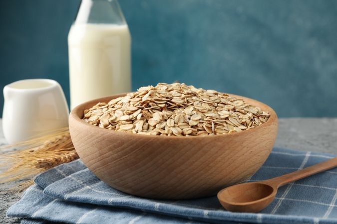 Composition with oatmeal flakes and milk on gray background. Cooking breakfast