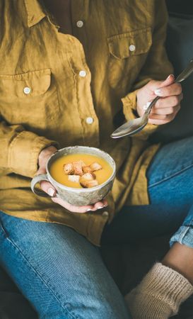 Woman in jeans with cup of squash soup