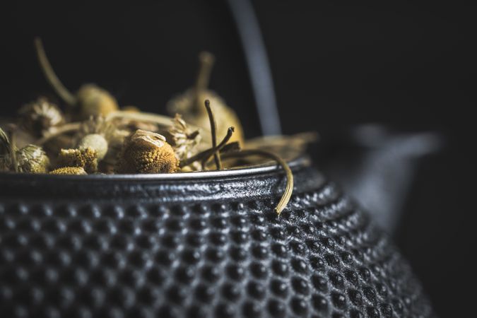 Spoonful of dried chamomile on brass teapot