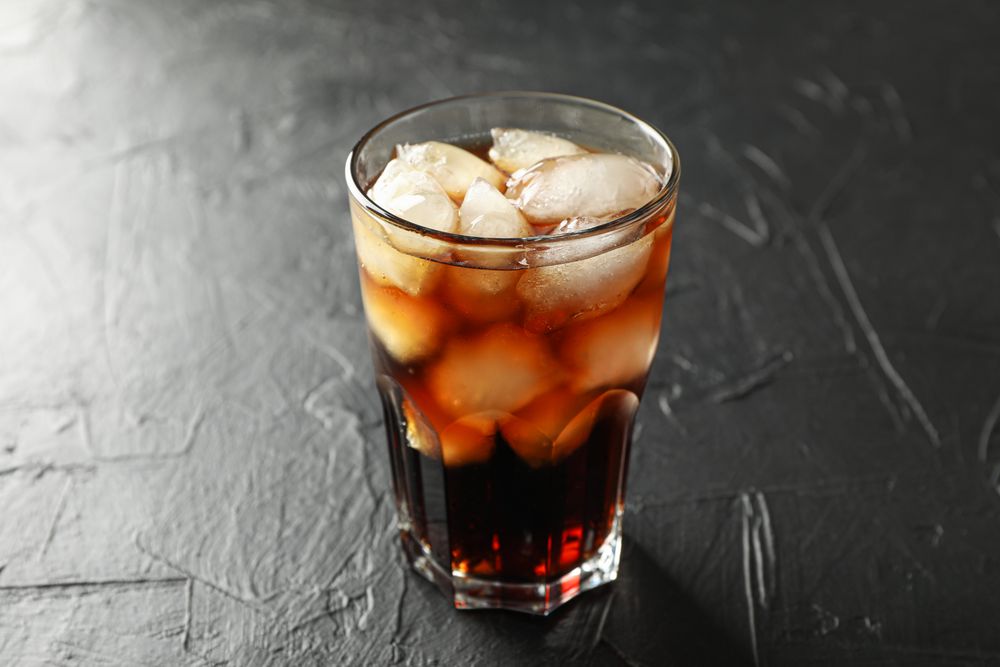 Glass of cold cola on cement background
