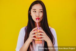 Portrait of a young woman drinking juice from a straw 4MDy15