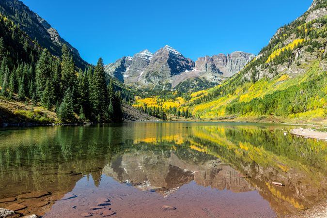 Rocky Mountain peaks with bright yellow wildflowers and lake
