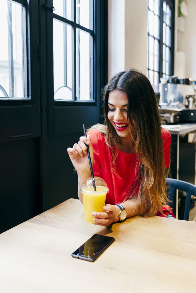 Happy woman sipping smoothie in cafe
