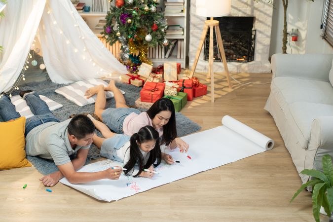 Happy Asian family drawing on paper together in the living room