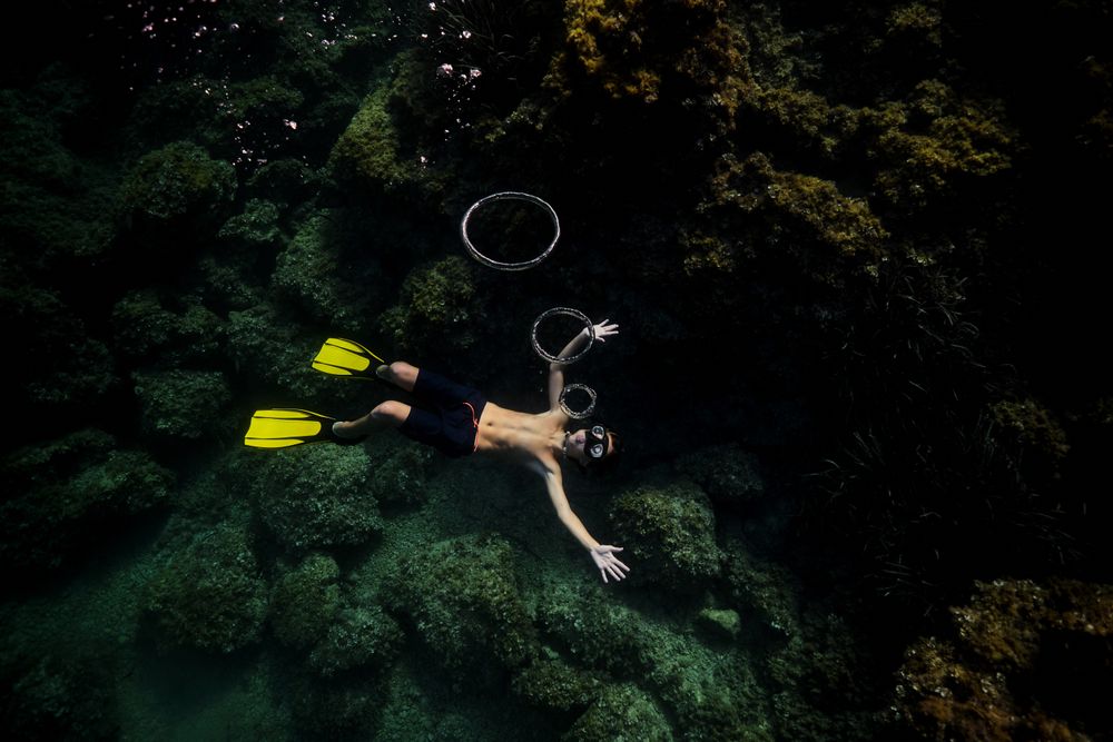 Man in snorkeling mask blowing bubbles underwater