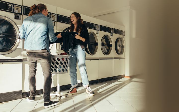 Happy couple doing laundry together inside laundromat