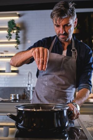 Man salting food in saucepan