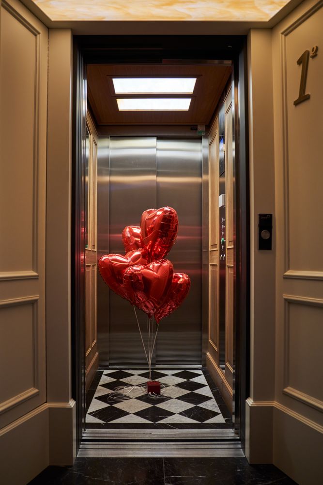 Doorway of hotel room leading to lift with red balloons