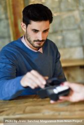 Man in sweater paying using smartphone 4jPdJ0