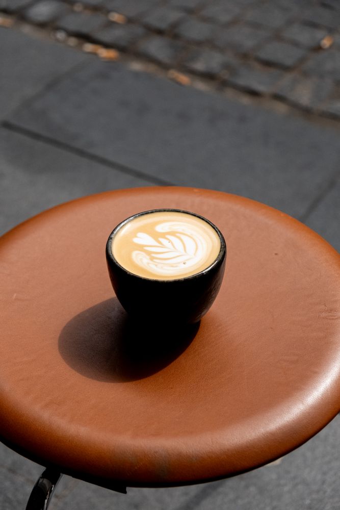 Cappuccino with heart swirl resting on sunny leather stool