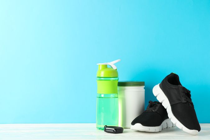 Sport lifestyle accessories on wooden table against blue background