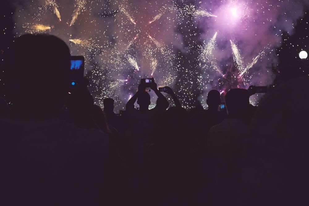 Back of audience taking pictures of stage with fireworks