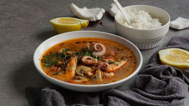Soup of octopus and shrimps near rice and lemon