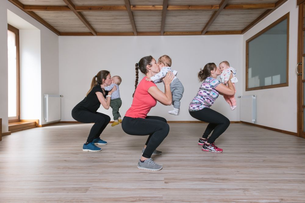 Mothers lifting babies in gym