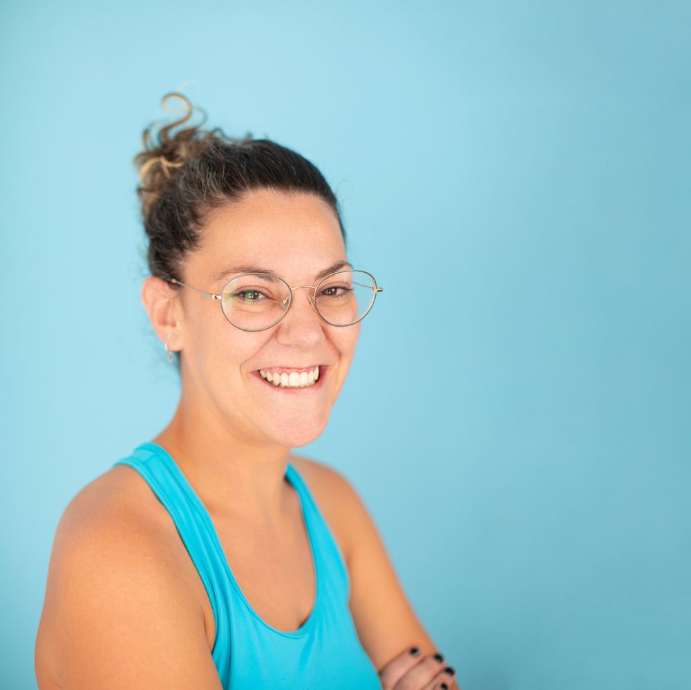 A woman wearing glasses smiles happily and confidently after receiving a manual therapy session at a physiotherapy clinic