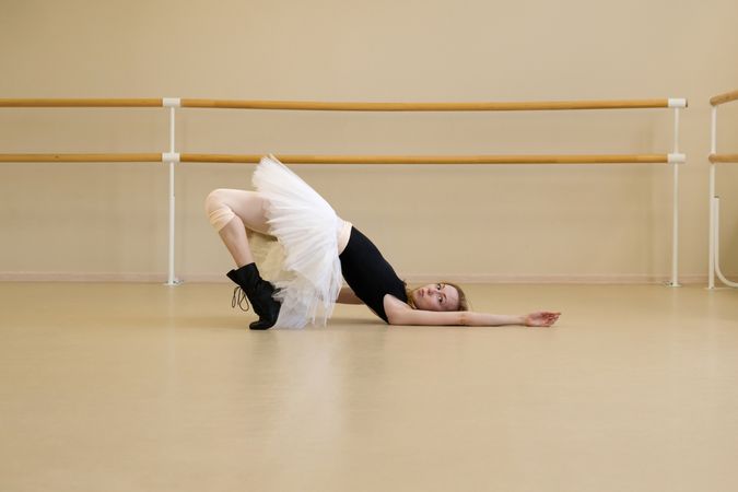 Ballerina in shoes and tutu, lying on floor