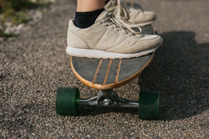 Anonymous woman riding longboard on asphalt road
