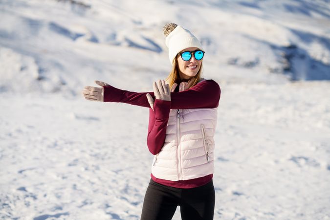Female in snowsuit stretching arms on snowy mountain