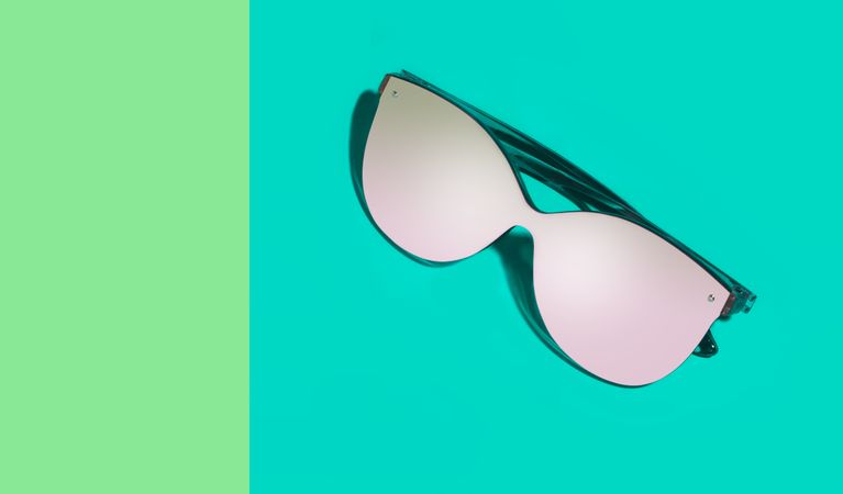 Stylish eyeglasses on green background