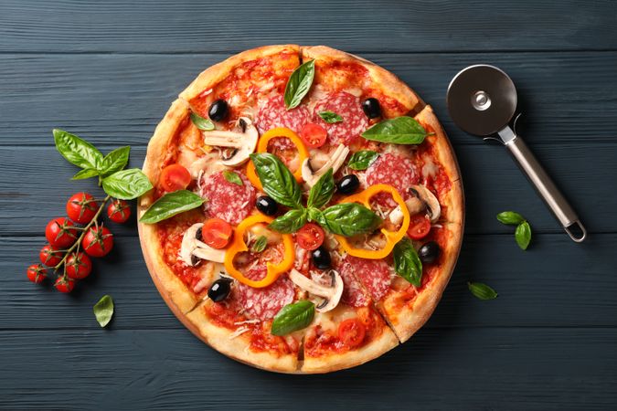 Delicious pizza, cutter and tomatoes on wooden background, copy space