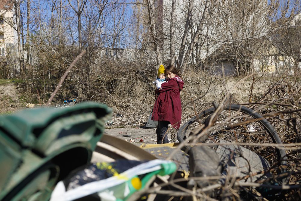 Woman holding her baby looking at rubble