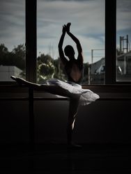 Ballerina doing ballet stretching exercise on barre