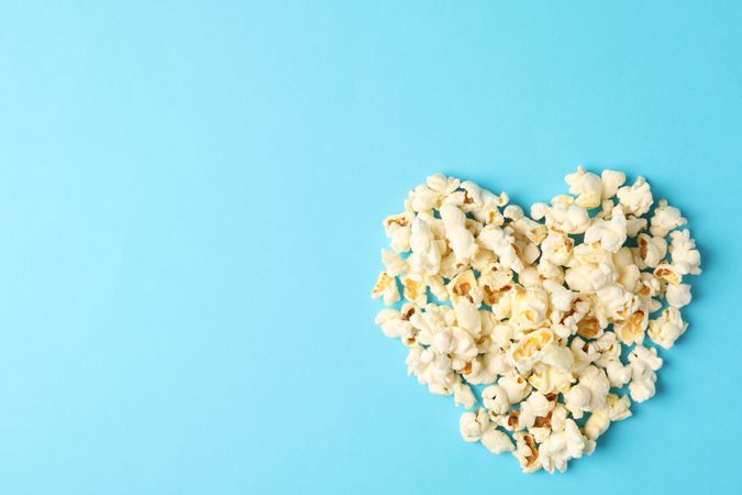 Flat lay composition with popcorn heart on blue background, space for text