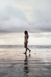 Side view of a young woman walking on the beach