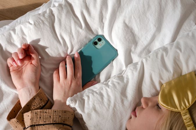 Woman asleep with phone, wearing eye mask