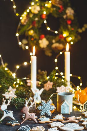 Candle-lit Christmas table with cookies, lights, and wreath