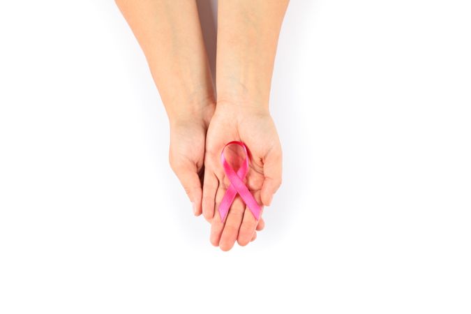 Female hands hold pink awareness ribbon, isolated on blank background