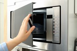 Young woman hand close the modern microwave