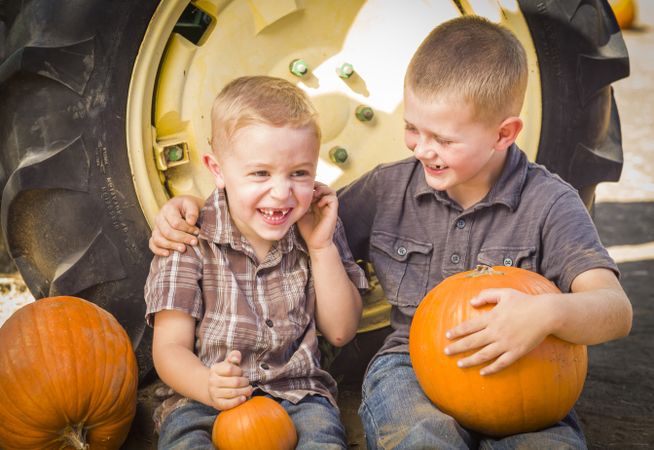 Two Boys Having Fun at the Pumpkin Patch on an Autumn Day.