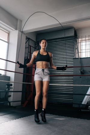 Female boxer jumping rope in boxing ring