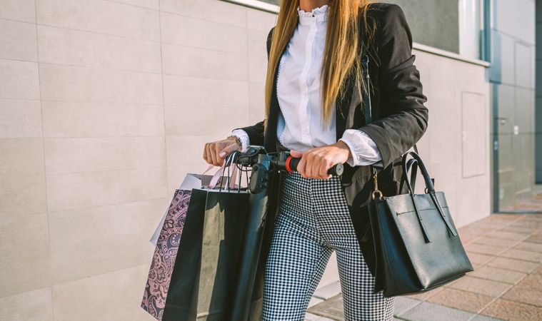 Unrecognizable woman with shopping bags on electric scooter