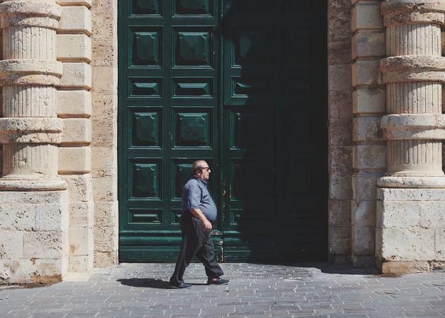 Sideview of middle aged man walking next to grand green door