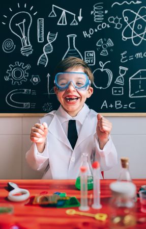Happy kid with glasses laughing behind of experiments table