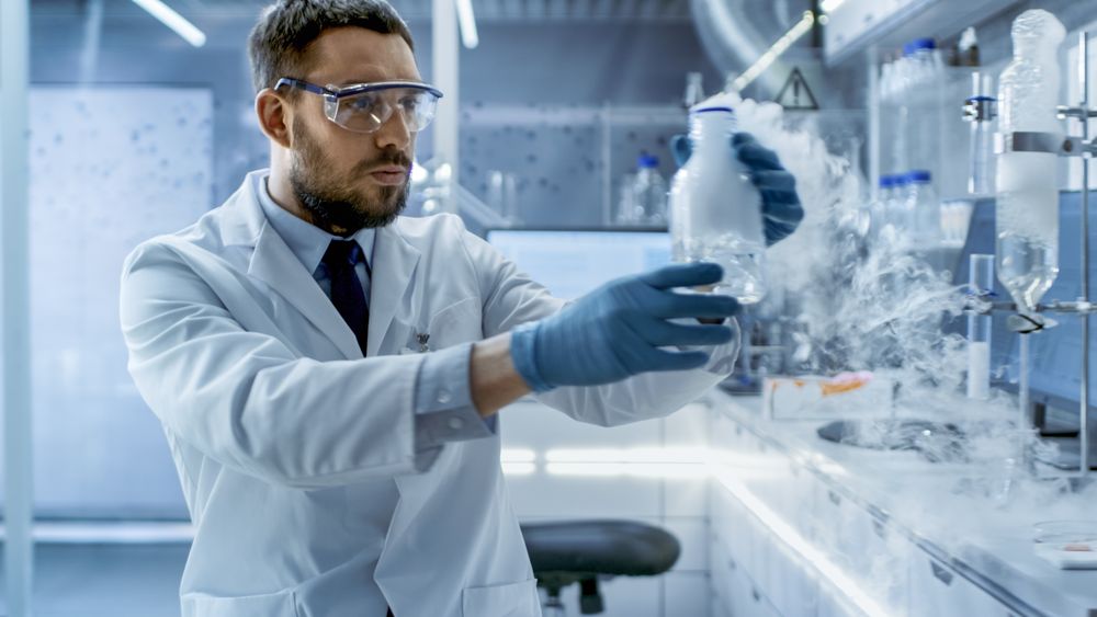 In a Chemical Research Laboratory Scientist Holds Smoking Compound in Beaker.