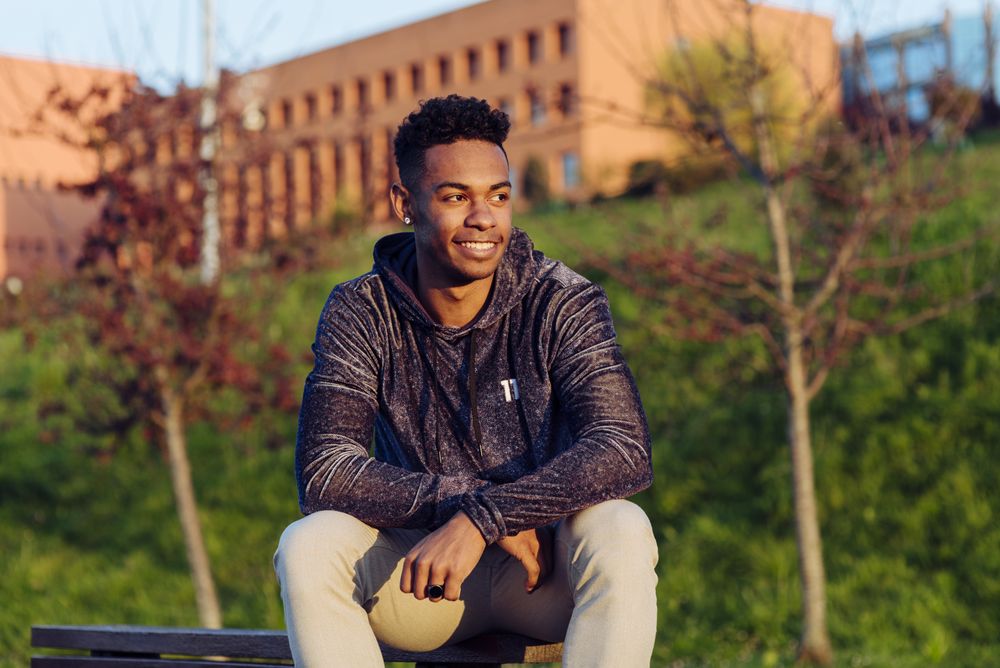 Young Black man sitting on bench with skateboard