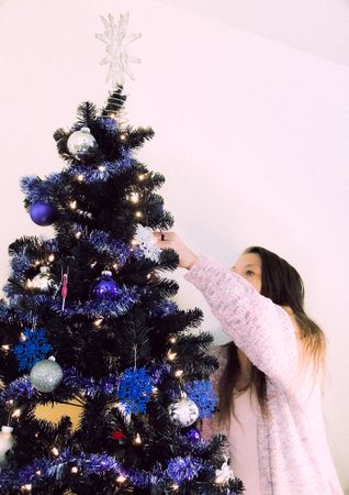 Woman preparing Christmas tree with blue baubles