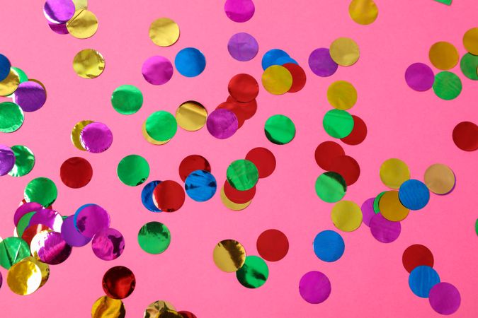 Multicolored glitter on pink background, close up