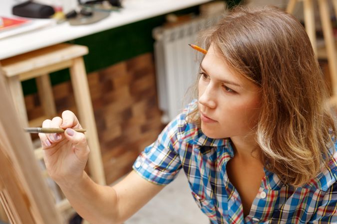 Female artist painting in plaid shirt