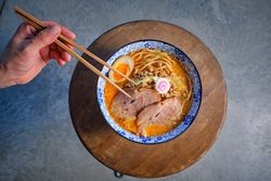 Anonymous person eating appetizing Asian noodle soup with chopsticks
