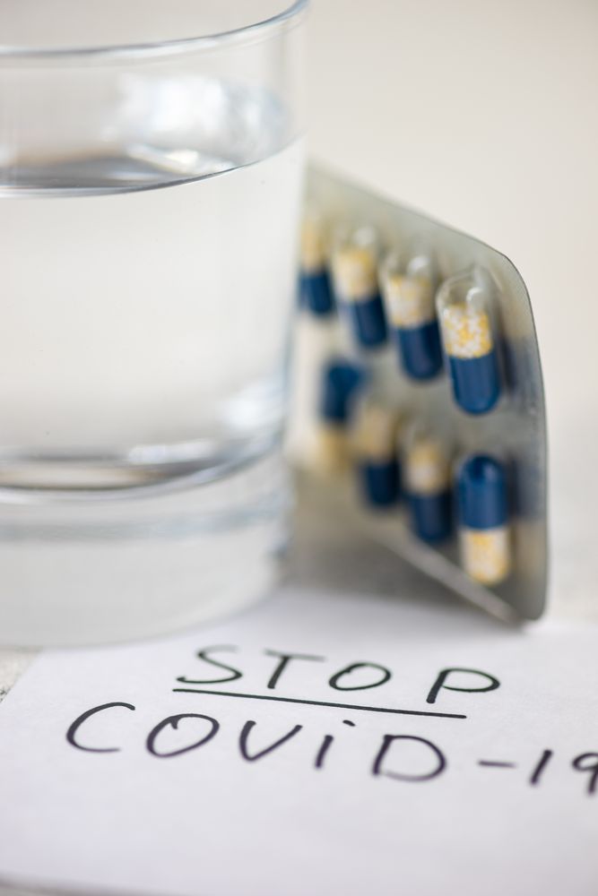 Pills and glass of water with covid-19 note
