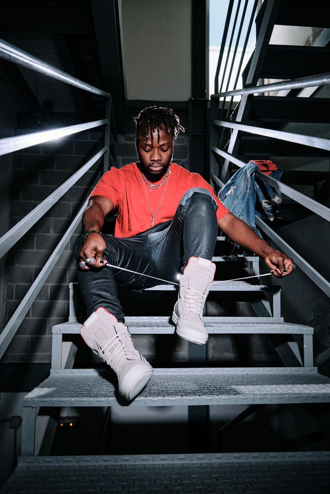 Stylish man in boots sitting on stairs