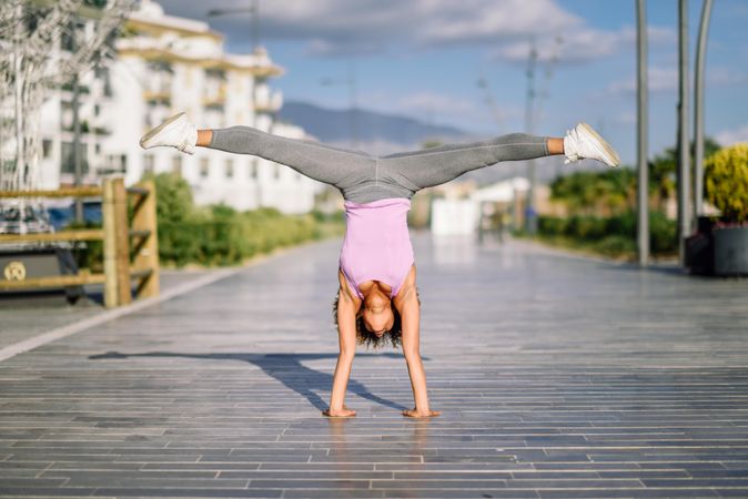 Woman in one handed handstand outside