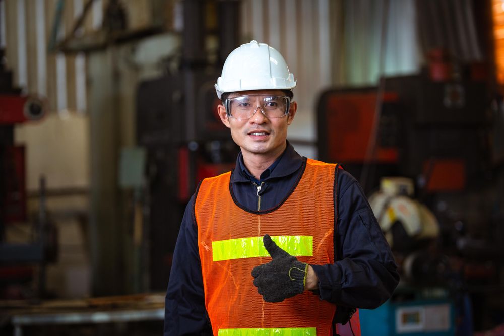 Asian man in hard hat and high vis jacket giving the thumbs up